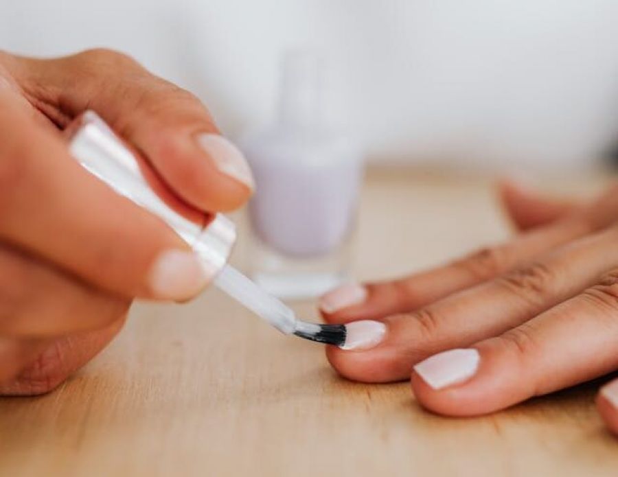 A woman applying white mail polish to her fingernails