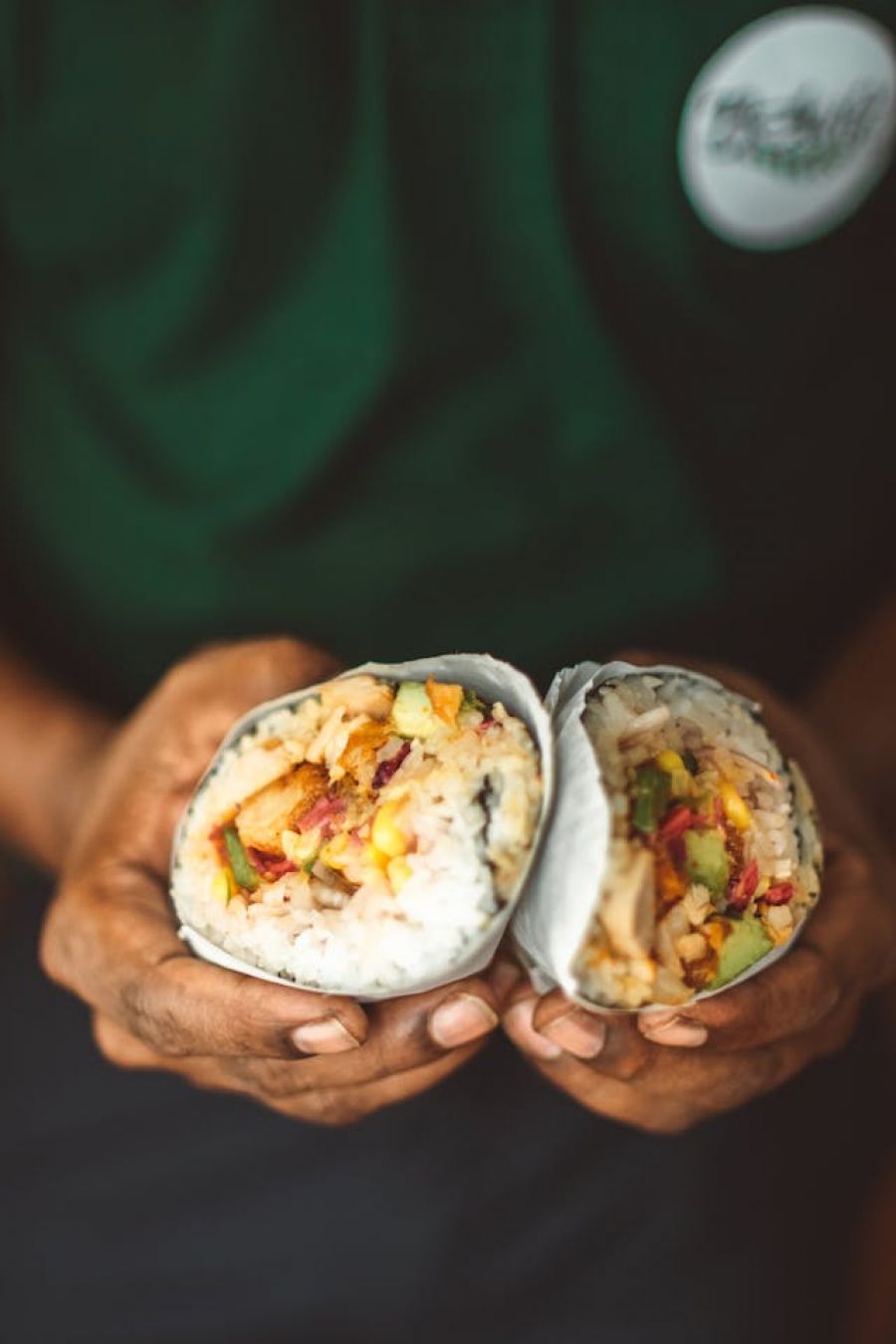 worker holding a burrito that has been cut on half