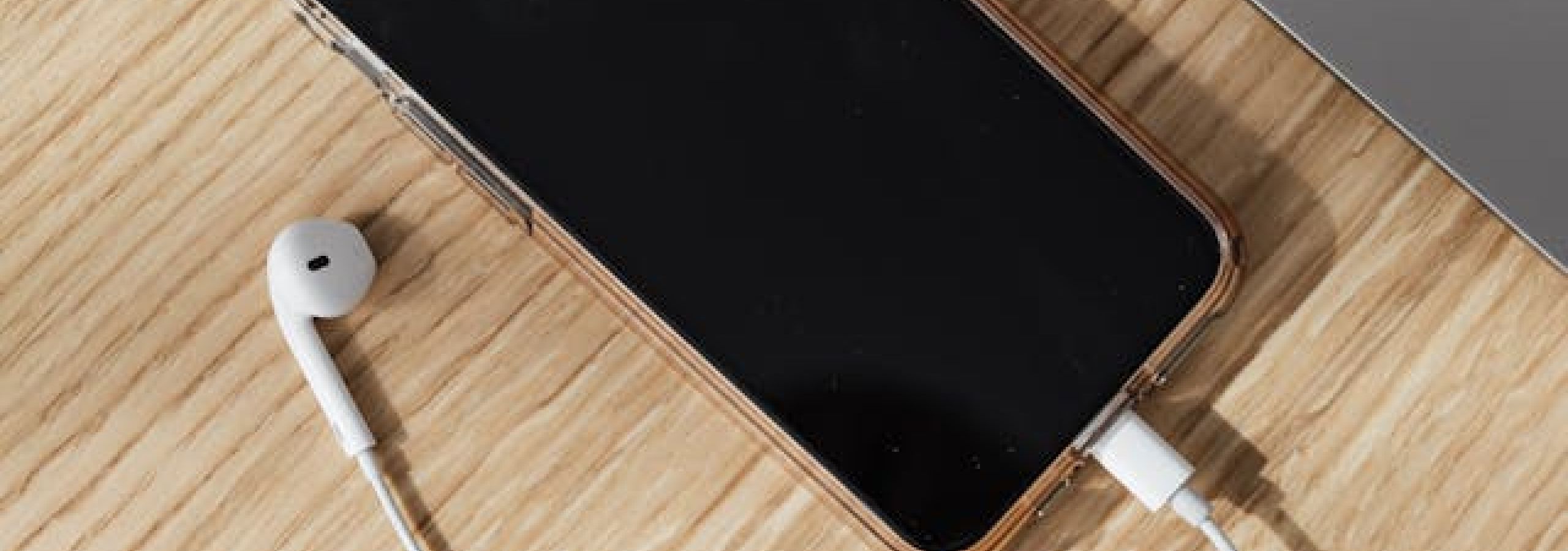 phone with headphones attached and a mac laptop