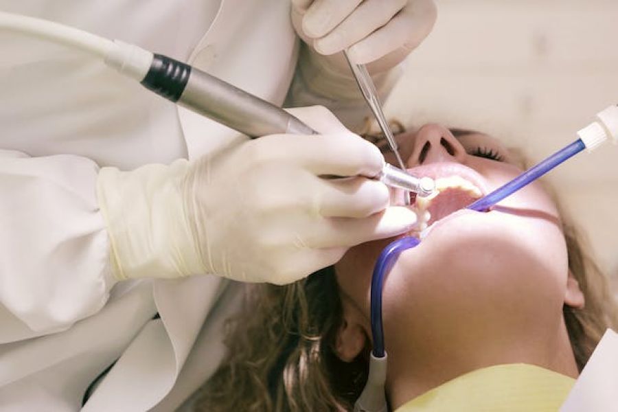 A dentist operating a drill in a woman's mouth