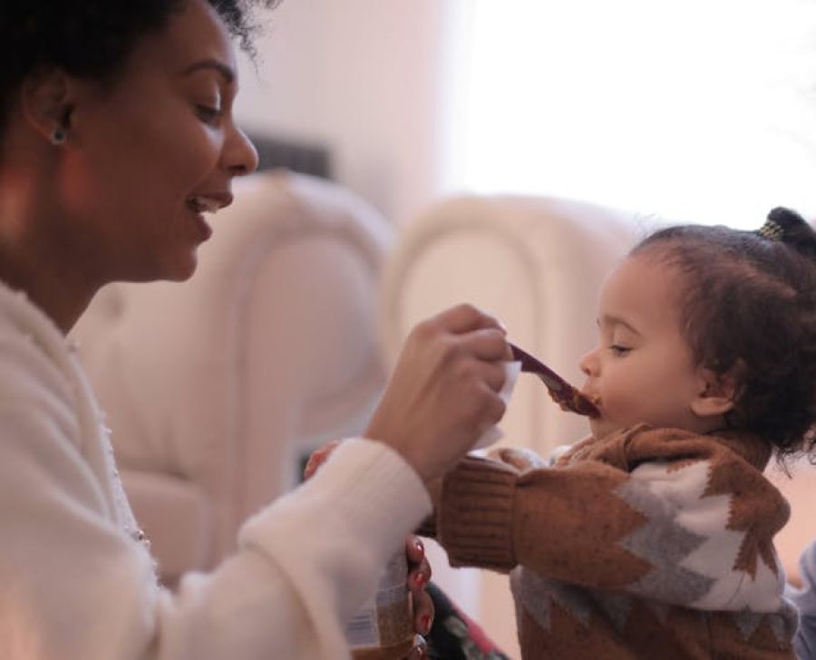 photo of woman feeding her child baby food