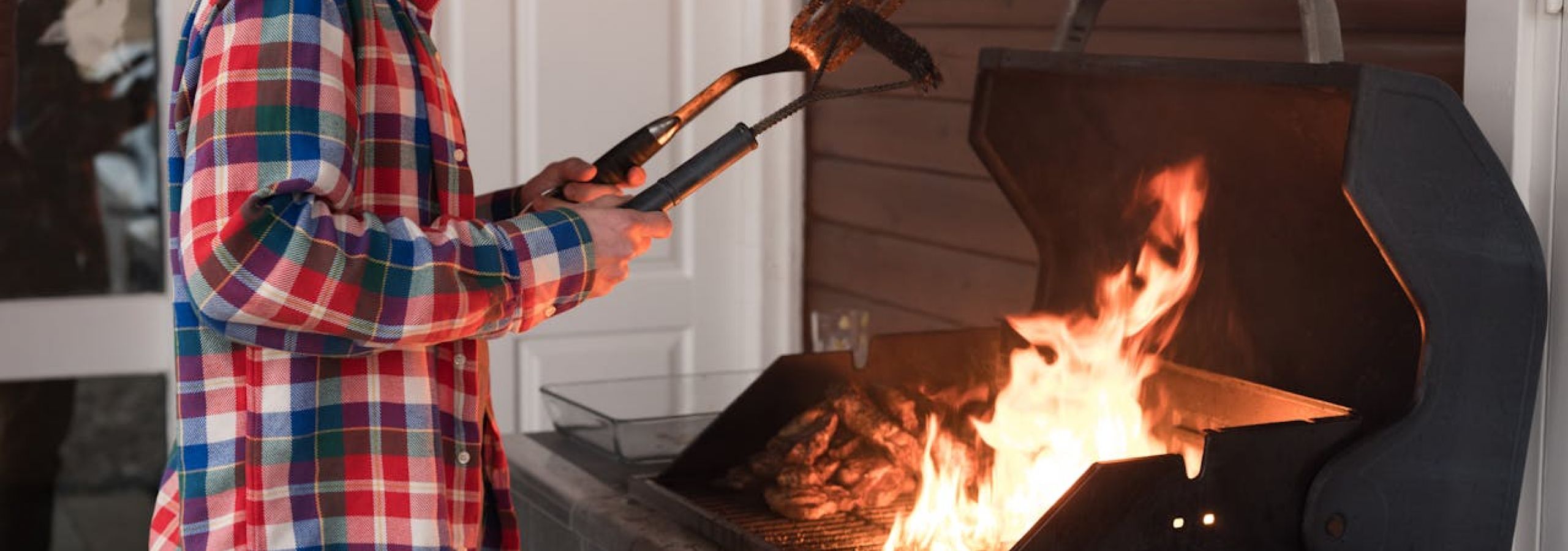 a man is standing over a grill with a spatula and a grill brush