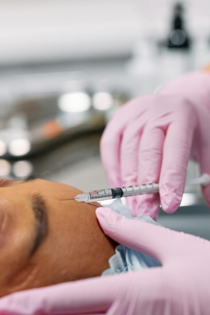A woman is given a botox injection in the forehead